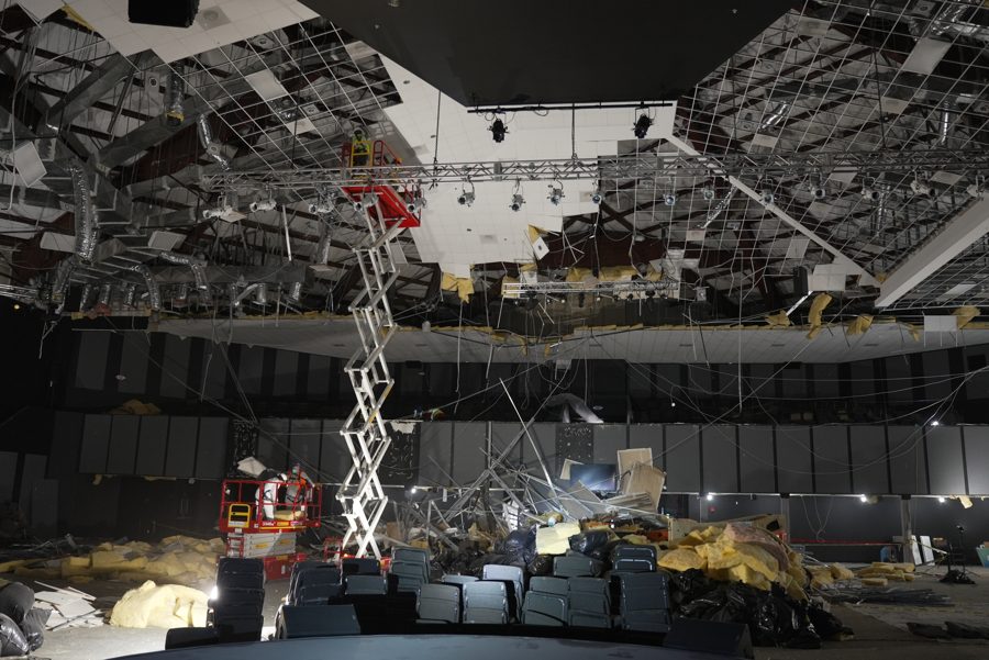 Workers on a lift assessing the collapsed ceiling grid and hanging insulation inside the Lighthouse Church sanctuary after Hurricane Beryl